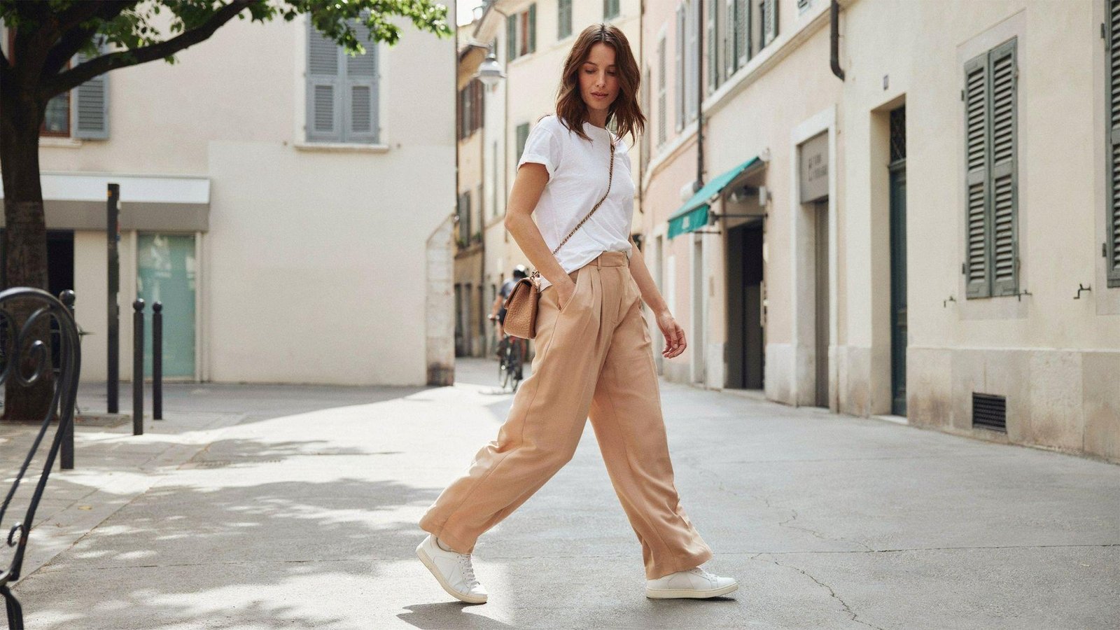 "Woman wearing wide leg pants with a tucked white t-shirt and white sneakers in a casual street style outfit"
