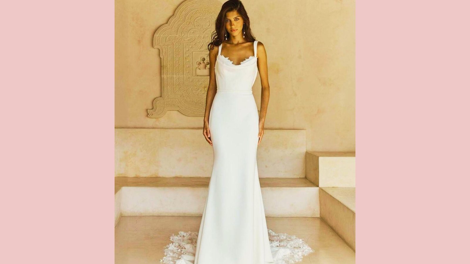Bride in sleek sheath gown with square cowl neckline, lace trim, thick straps, lace train, standing on stairs