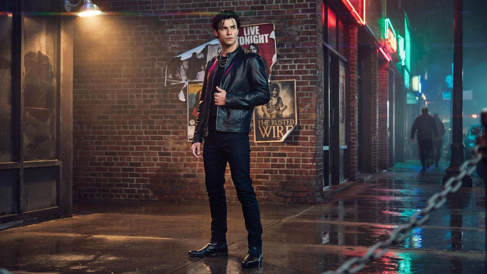"Man wearing all-black rocker outfit with leather jacket, slim black jeans, and boots inspired by classic 80s fashion"