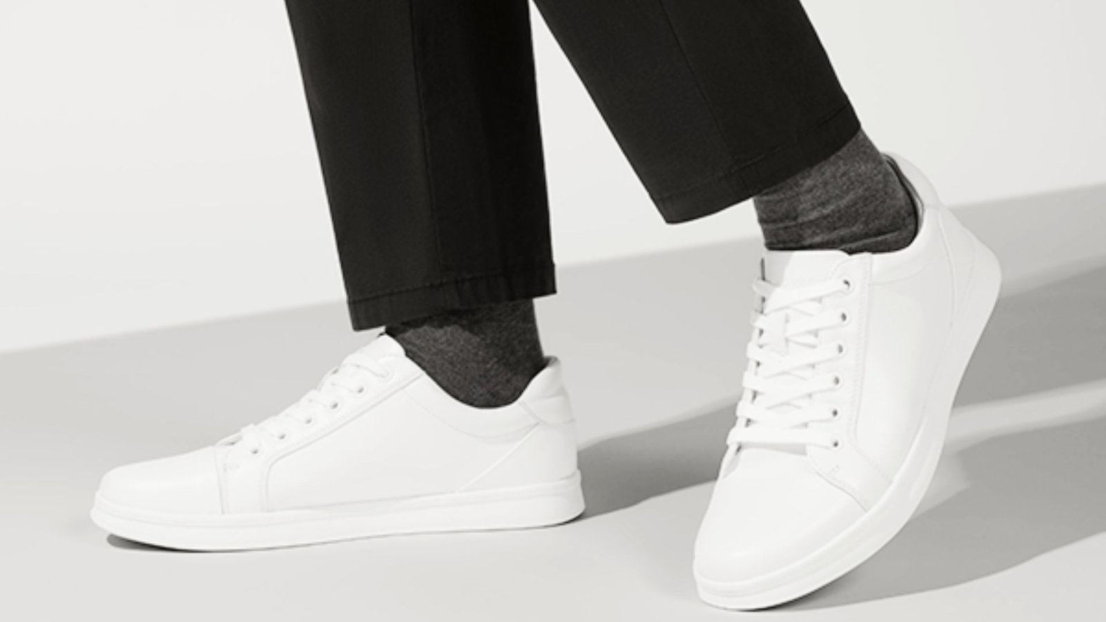 A person dressed in black pants and white sneakers, highlighting a modern and casual fashion choice.
