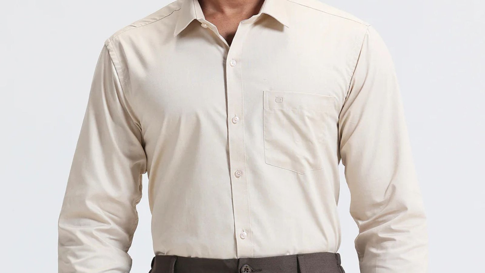 A man in a beige colored shirt, embodying a professional and fashionable look.