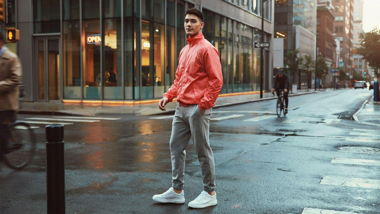 "Man wearing neon windbreaker with neutral joggers and white sneakers in retro 80s streetwear style"