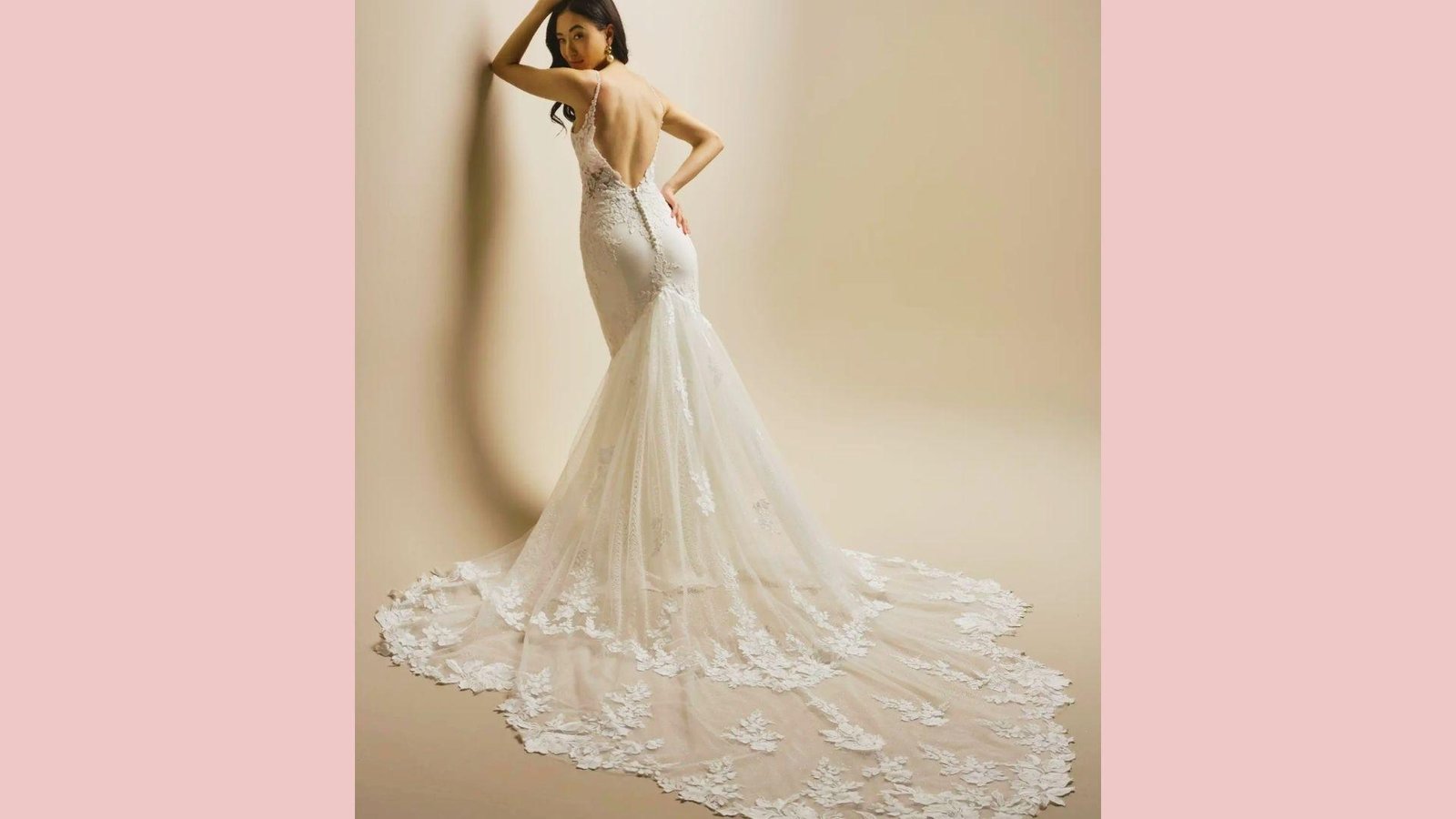 Model showing back of fitted mermaid gown with low V-back, delicate lace appliqués, spaghetti straps, dramatic flowing train