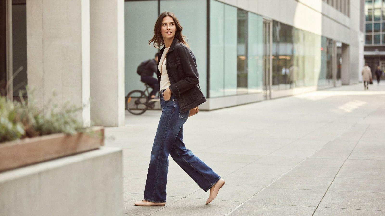 "Woman styling wide leg pants with a denim jacket for a casual layered street style look"