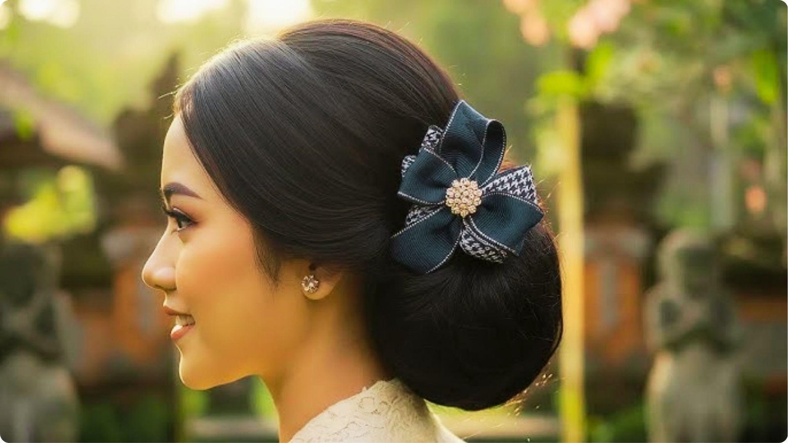 Side profile of a woman with a sleek low bun adorned with a navy blue and houndstooth bow hair accessory with a pearl center.