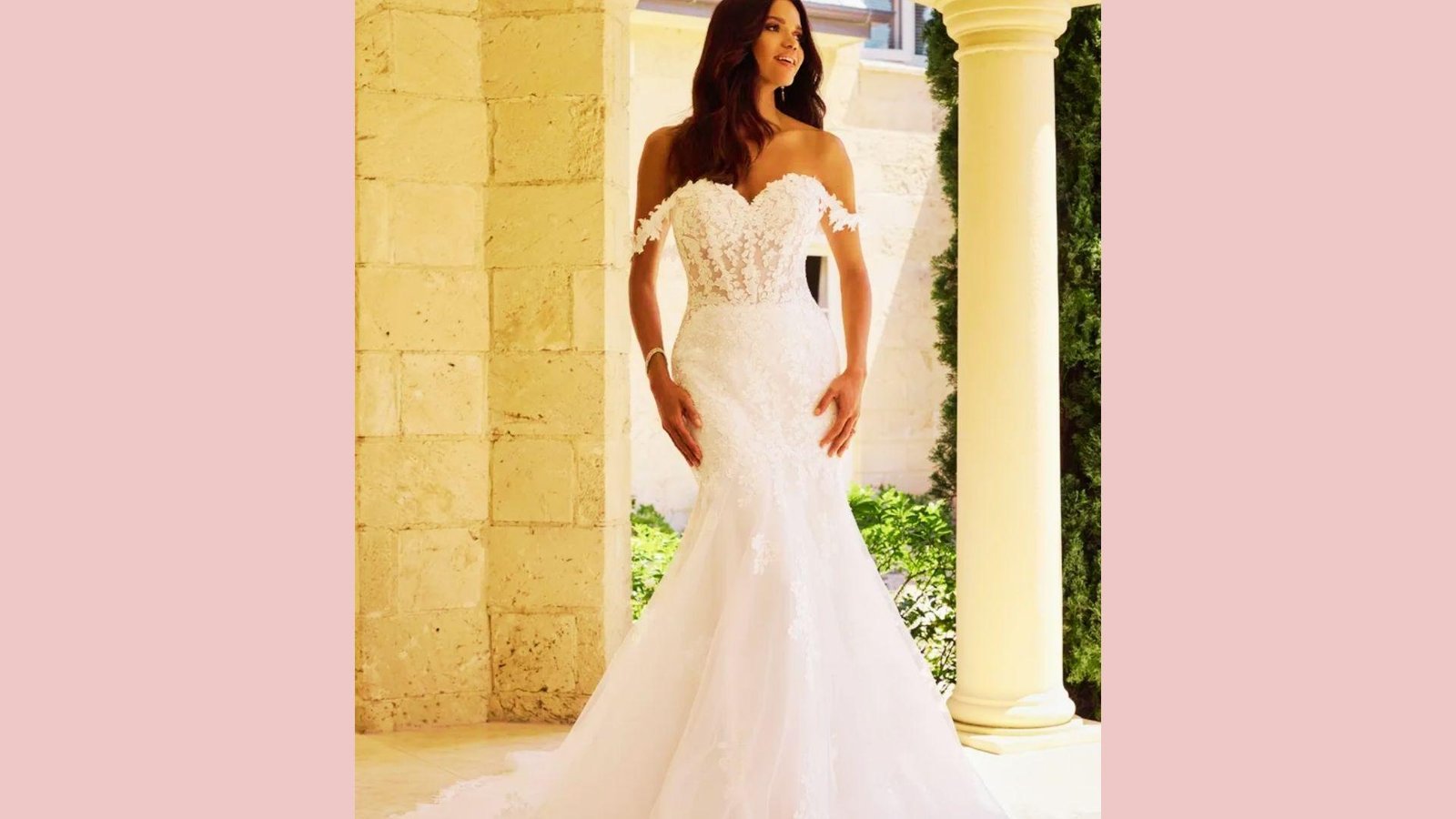 Bride in fitted mermaid gown with off-shoulder lace sweetheart neckline, illusion bodice, tulle skirt, standing by stone columns
