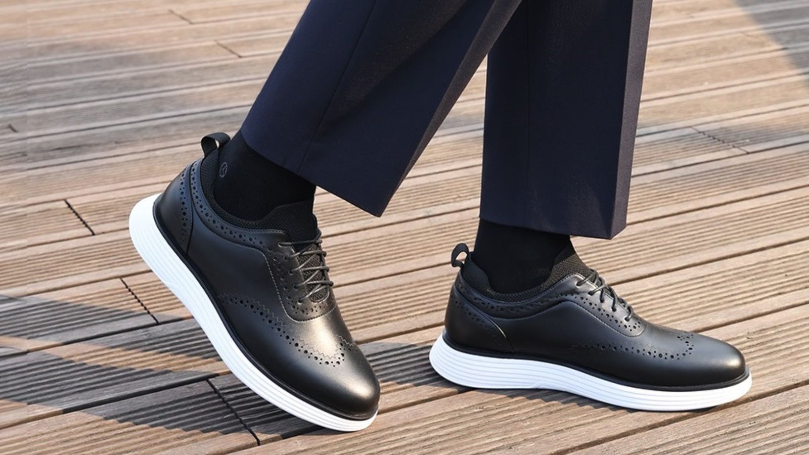 Close-up of black oxford sneakers with white soles paired with navy dress pants and black socks