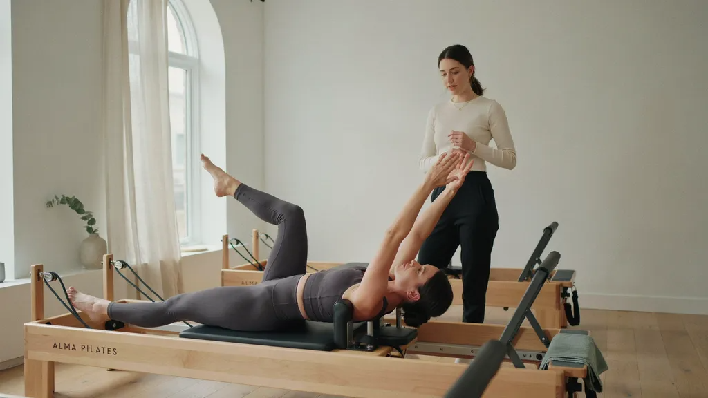Woman doing Pilates in fitted activewear with focus on posture, alignment, and movement control.