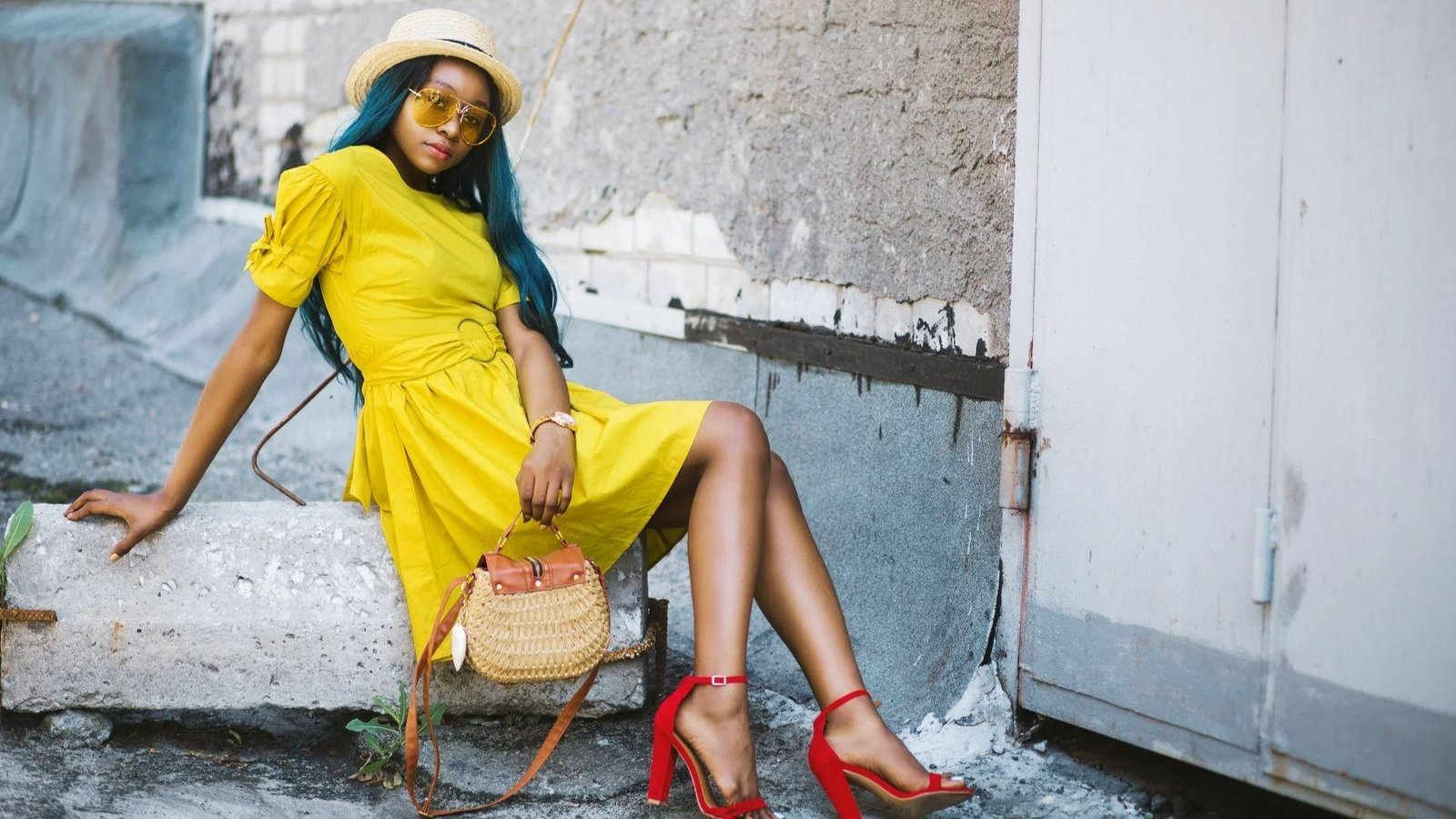 Woman styling yellow dress with shoe in bright fashion bedroom scene.