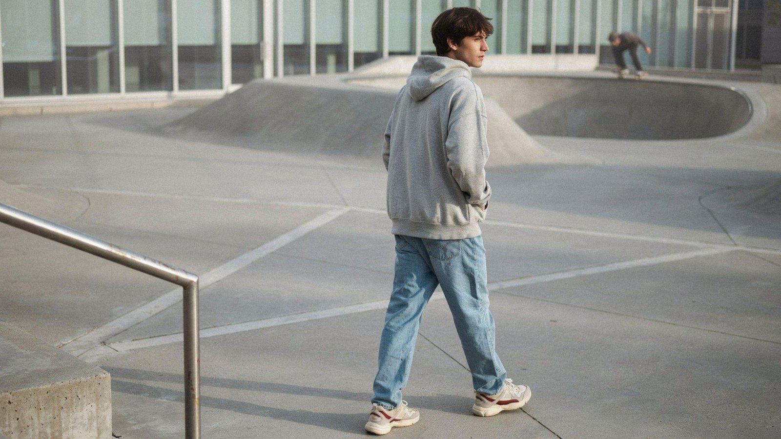 "Young man wearing light blue jeans styled with an oversized hoodie and chunky sneakers in a casual streetwear urban setting."