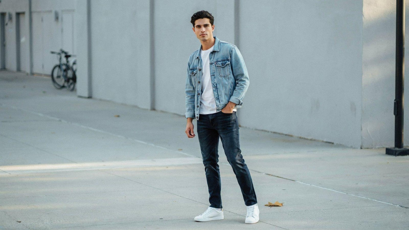 "Man styling modern double denim outfit with contrasting denim jacket and jeans inspired by classic 80s fashion"