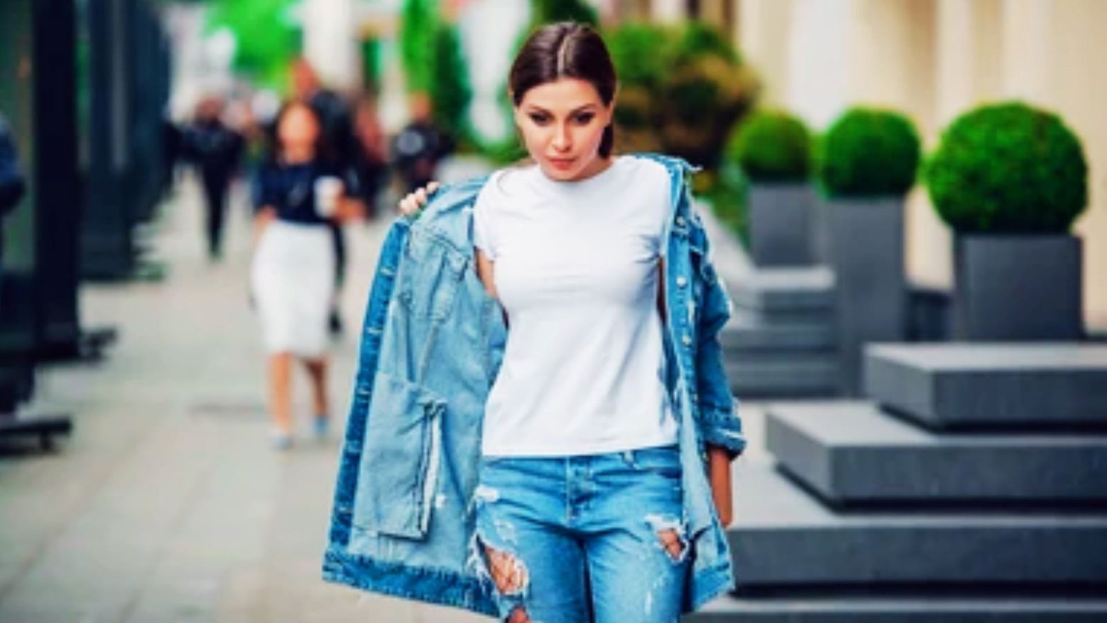 Woman styling a light wash denim vest with dark denim jeans and a white t-shirt.
